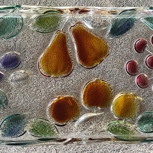 May include: A rectangular glass serving tray with a fruit design. The tray features pears, cherries, and other fruits in shades of orange, red, and purple, along with green leaves. The tray has handles on each end.