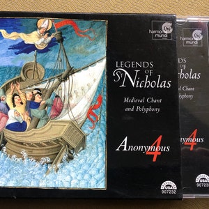 May include: A CD case with a black background and red text that reads "Legends of St. Nicholas Medieval Chant and Polyphony Anonymous 4". The front cover features a painting of a ship with a saint in the sky.