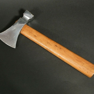 Puede incluir: Un pequeño hacha de color plateado con un mango de madera. El hacha tiene una hoja afilada y una cabeza roma.