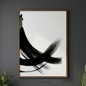 Vertical wall art in a moody dark living room featuring a large wood-framed black and white abstract brushstroke print above a black sofa. The interior includes a fiddle leaf fig, snake plant, and a marble coffee table with a candle and eucalyptus, creating a luxury modern home office atmosphere.
Below the wall art, there is a text: "created by Agnes Szafranska - arteprinte.com".
