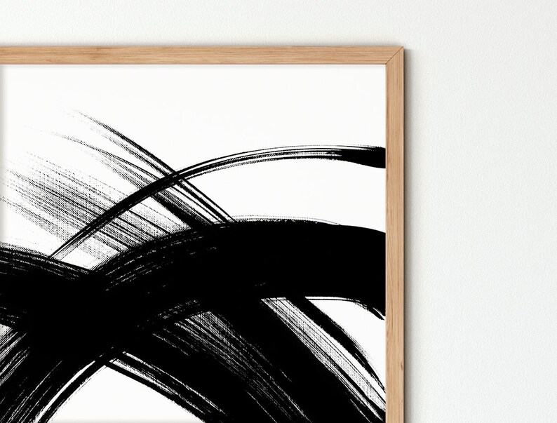 A close-up of the abstract black and white painting with bold brushstrokes in a wooden frame.