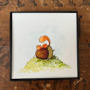 May include: A watercolor painting of a red squirrel sitting on top of an acorn. The squirrel is looking to the left and has a bushy tail. The acorn is brown and has a cap on top. The squirrel and acorn are sitting on a green grassy hill.