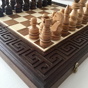 Könnte beinhalten: Ein Schachspiel aus Holz mit dunkelbraunen und hellbraunen Figuren auf einem Holzbrett mit einem dekorativen Rand. Das Brett ist geschlossen und hat einen Verschluss.