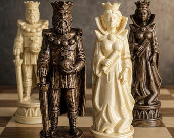 Op de afbeelding: Vier schaakstukken op een bord. Er zijn twee koningen en twee koninginnen afgebeeld, met van elk één in een donkerbruine afwerking en één in een crèmekleurige afwerking. De figuren hebben gedetailleerde gewaden, kronen en houden symbolische voorwerpen.
