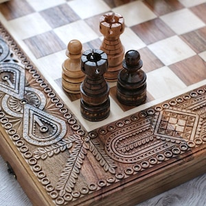May include: A wooden chessboard with intricate carvings on the edges. The board is open and shows a few chess pieces, including a black rook, a white pawn, and a white rook.