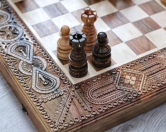 May include: A wooden chessboard with intricate carvings on the edges. The board is open and shows a few chess pieces, including a black rook, a white pawn, and a white rook.
