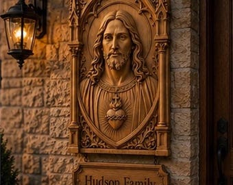 May include: A rectangular wooden wall plaque featuring a carved relief of the Sacred Heart of Jesus within a gothic arch frame. Below the main carving, a smaller rectangular wooden sign is suspended, displaying the text Hudson Family in dark letters.