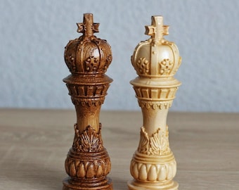 May include: Two wooden chess pieces, a king and a queen, with intricate carvings. The king is a dark brown colour, while the queen is a light natural wood colour.