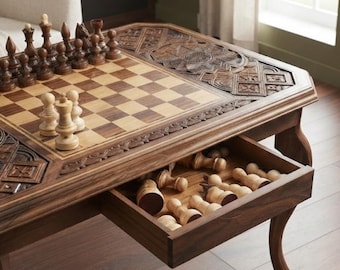 May include: A wooden chess table featuring a checkered board surface with intricate carved patterns on the borders. The table includes a pull-out drawer containing light-colored wooden chess pieces, while dark and light pieces are set on the board.