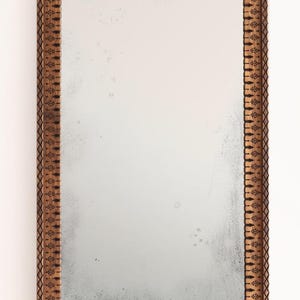May include: A rectangular mirror with a brown wooden frame. The frame has a decorative carved design.