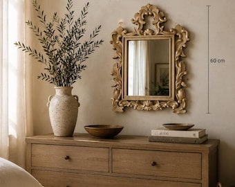 May include: A rectangular wall mirror with an ornate, carved light brown frame featuring scrollwork and leaf motifs. The mirror measures 50 cm in width and 60 cm in height, as indicated by the text and lines visible next to the frame.