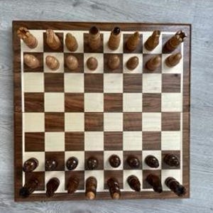 Könnte beinhalten: Ein Schachbrett aus Holz mit einem hellbraunen und dunkelbraunen Schachbrettmuster. Die Schachfiguren sind aus Holz und in ihren Startpositionen angeordnet.