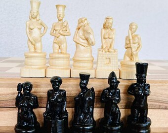 May include: A set of ten chess pieces arranged in two rows, featuring five light-coloured figures and five dark-coloured figures. Each piece is sculpted in the form of a human or animal figure, standing on a circular base, with detailed textures.
