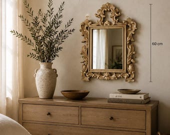May include: A rectangular wall mirror with an ornate, carved light brown frame featuring scrollwork and leaf motifs. The mirror measures 50 cm in width and 60 cm in height, as indicated by the text and lines visible next to the frame.