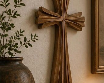 May include: A wall-mounted wooden cross featuring a multi-layered, sunburst-inspired design with deep, carved grooves. The cross is crafted from medium-toned brown wood with a visible grain, showcasing a symmetrical, geometric, and dimensional structure.