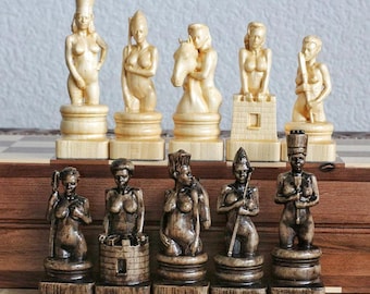May include: A set of wooden chess pieces featuring nude figures. The pieces are carved in a realistic style and are painted in a natural wood finish. The set includes a king, queen, rook, bishop, knight, and pawn.