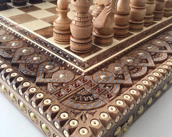 May include: A wooden chess set with intricate carvings on the board and pieces. The board is made of dark wood with a light wood inlay. The pieces are made of light wood and have a natural finish.