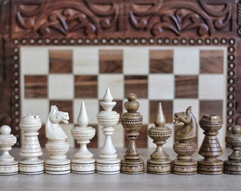 May include: A set of wooden chess pieces in a variety of styles, including a knight, bishop, and rook. The pieces are arranged in a row on a wooden surface in front of a chessboard.