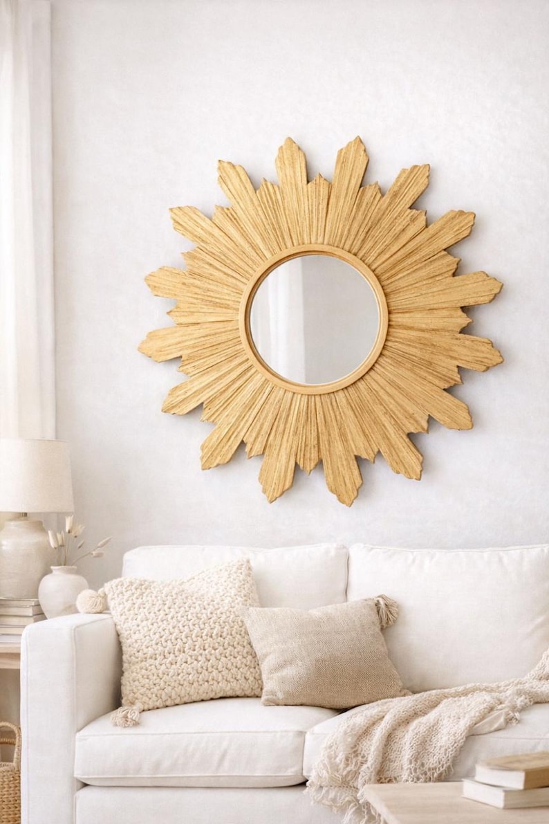 May include: A round wall mirror featuring a decorative sunburst frame with textured, golden-toned rays radiating outward from the central glass. The frame consists of numerous pointed, wooden-like segments arranged in a circular pattern.