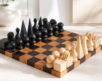 May include: A wooden chess set featuring a checkered board with alternating dark brown and light tan squares. The pieces are crafted in abstract geometric shapes, including spheres, cubes, cones, and tall spires, finished in solid black and natural light wood.
