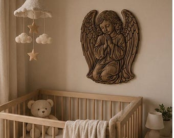May include: A wooden wall plaque featuring a relief carving of a praying angel with large wings, positioned above a wooden crib containing a teddy bear and a white blanket, with a hanging mobile of white clouds and stars suspended nearby.