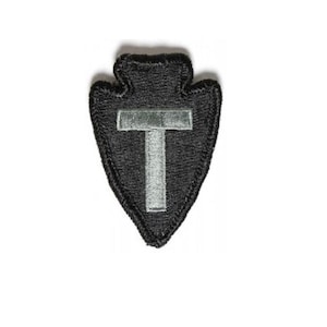 May include: A black embroidered patch in the shape of an arrowhead with a white letter "T" inside.