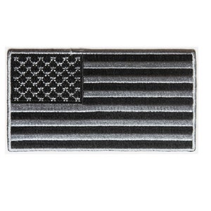 May include: A black and white embroidered American flag patch. The stars are black and the stripes are white and gray.
