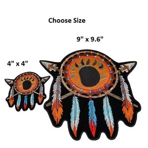 May include: Two embroidered patches featuring a Native American dreamcatcher with a bear paw print in the center. The larger patch is 9 inches by 9.6 inches and the smaller patch is 4 inches by 4 inches. Both patches have a black background with brown, orange, and blue feathers.
