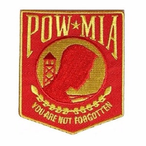 May include: Red and gold embroidered patch with the words "POW*MIA" and "You Are Not Forgotten". The patch features a silhouette of a prisoner of war with a guard tower in the background.