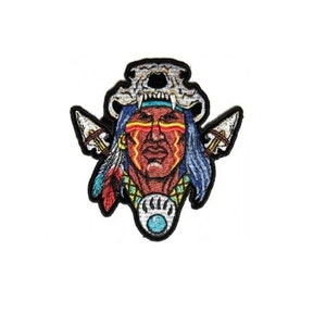 May include: Embroidered patch featuring a Native American warrior with a skull headdress, red and yellow face paint, and a turquoise pendant. The warrior is holding two spears.