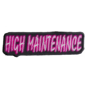 May include: Black and white embroidered patch with the text "HIGH MAINTENANCE" in pink.