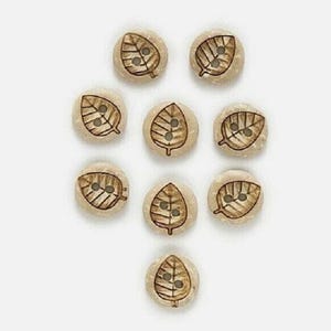 May include: Nine round, light-colored buttons with a leaf design. Each button has a brown leaf pattern with two small holes for sewing. The buttons are arranged on a white background.
