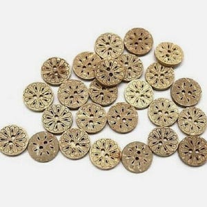 May include: A collection of round, wooden buttons with a floral design. The buttons are light brown with a darker brown etched pattern. Each button has four holes for sewing.