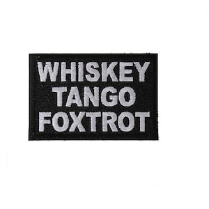 May include: Black patch with white text that reads "Whiskey Tango Foxtrot".