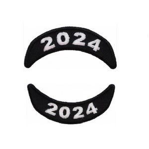 May include: Two black embroidered patches with white lettering. The patches are shaped like a half-circle and read "2024".
