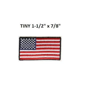 May include: A small embroidered American flag patch, measuring 1-1/2 inches by 7/8 inches. The flag is red, white, and blue with a black outline.