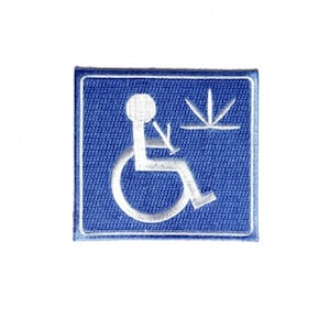 May include: Embroidered patch featuring the international symbol of access, a white figure in a wheelchair, on a blue square. The patch also includes a stylized graphic. The patch has a white border.