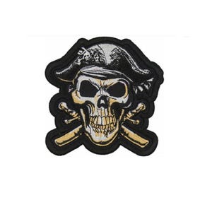 May include: Black and white embroidered patch of a skull wearing a pirate hat and holding crossed bones. The skull has a gold and white design.