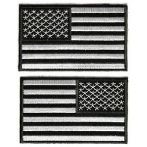 May include: Two embroidered patches featuring the American flag. Each patch has a rectangular shape with horizontal stripes and a field of stars in the upper left corner. The patches are in black and white.