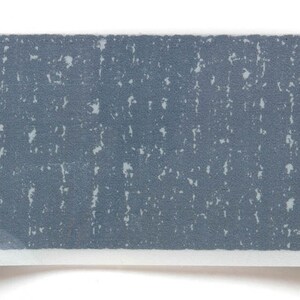 May include: A close-up of a gray textured surface with a white background. The surface has a speckled pattern.