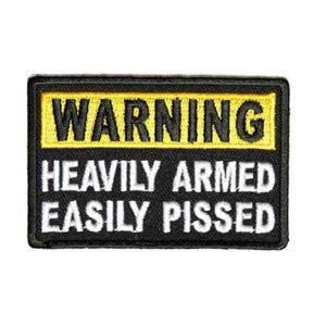 May include: A rectangular black patch with yellow and white text. The top section reads "WARNING" in black letters on a yellow background. The bottom section reads "HEAVILY ARMED EASILY PISSED" in white letters.