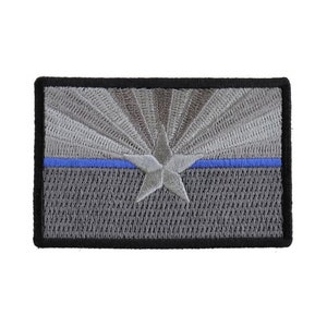 May include: An embroidered patch featuring the Arizona state flag with a thin blue line. The patch is gray with a white star and a blue stripe across the center.