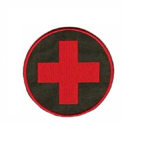May include: A red medical cross embroidered on a dark green circular patch.