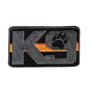 May include: Black and gray embroidered patch with the text "K9" and a black paw print. The patch has an orange stripe across the middle.