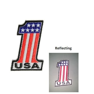 May include: A red, white, and blue embroidered patch with the number "1" and "USA" written below. The patch is reflective and has a star-spangled banner design.