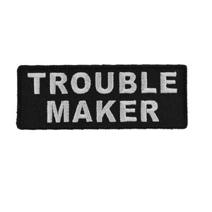 May include: Black embroidered patch with white text that reads "Trouble Maker".