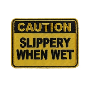 May include: Yellow and black caution sign with the text "CAUTION SLIPPERY WHEN WET" embroidered on it.