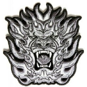 May include: Embroidered patch featuring a fierce, snarling gorilla face with flames. The design is in shades of gray and white, with detailed stitching creating a textured appearance. The patch has a black border and is suitable for jackets, bags, or other apparel.
