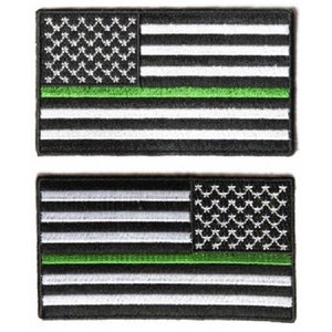 May include: Two embroidered patches featuring the American flag with a thin green stripe across the middle. The patches are black with white stars and stripes.