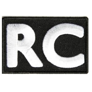 May include: Black embroidered patch with white letters "RC" in a rectangular shape.